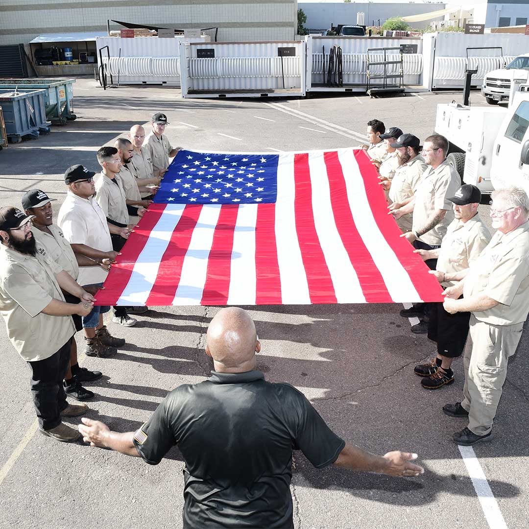 First Impression Ironworks Employees Holding A Large Flag