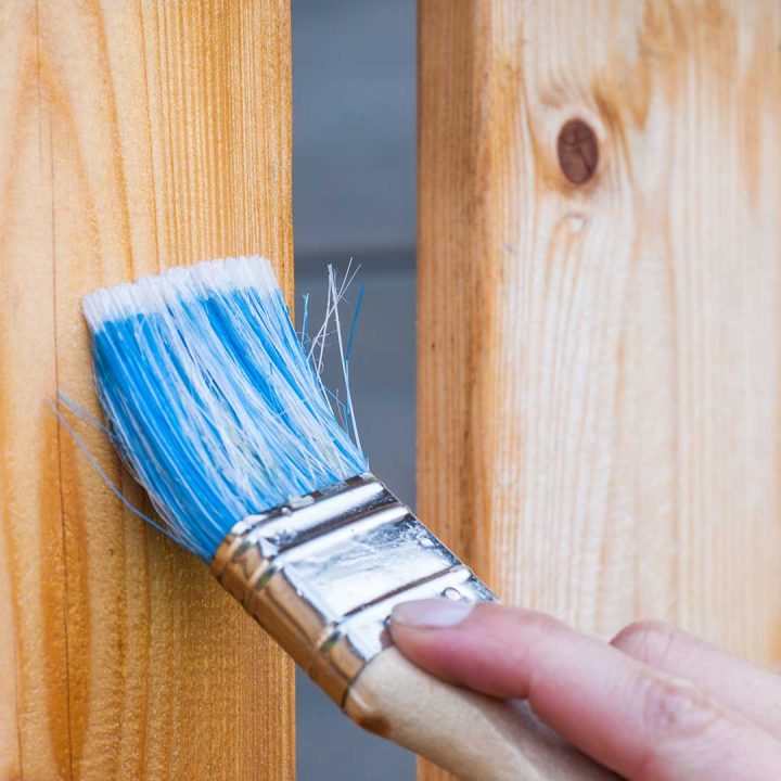 Brushing sealer onto wood with a brush