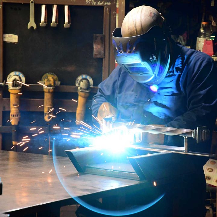 First Impression Ironworks employee welding a steel door part, which we ship nationally.