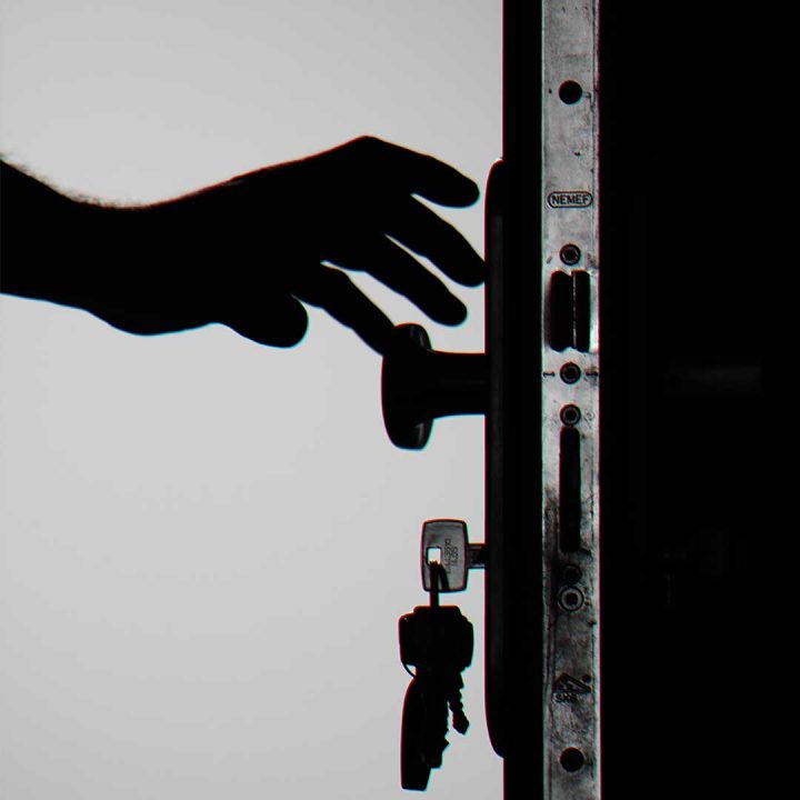 silhouette of a hand reaching to open a front door