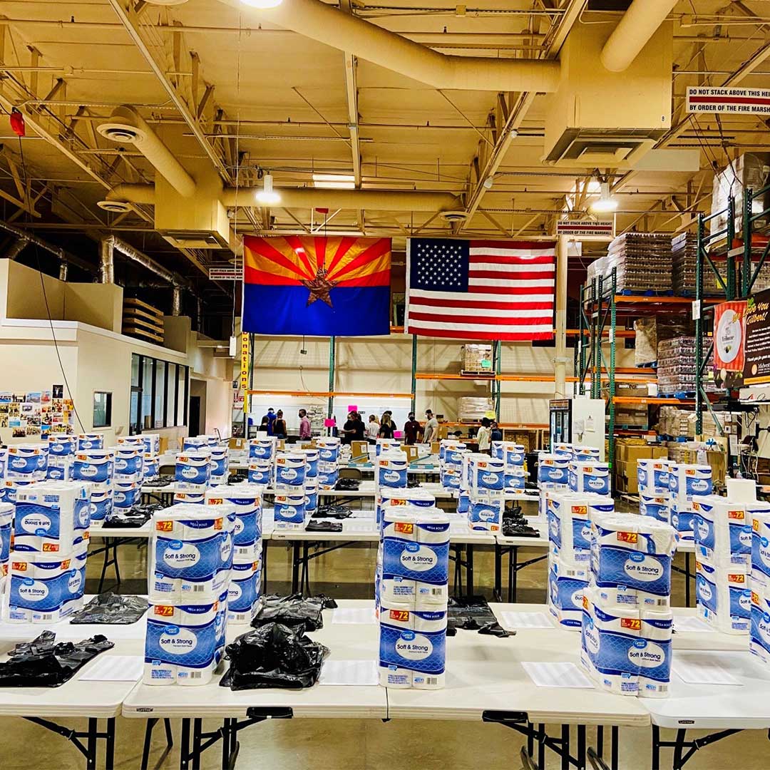 Warehouse filled with tables full of supplies to be packed for food boxes