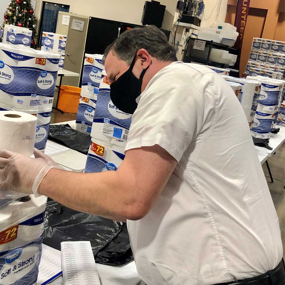 Volunteer stacking rolls of toilet paper to be added to donation boxes