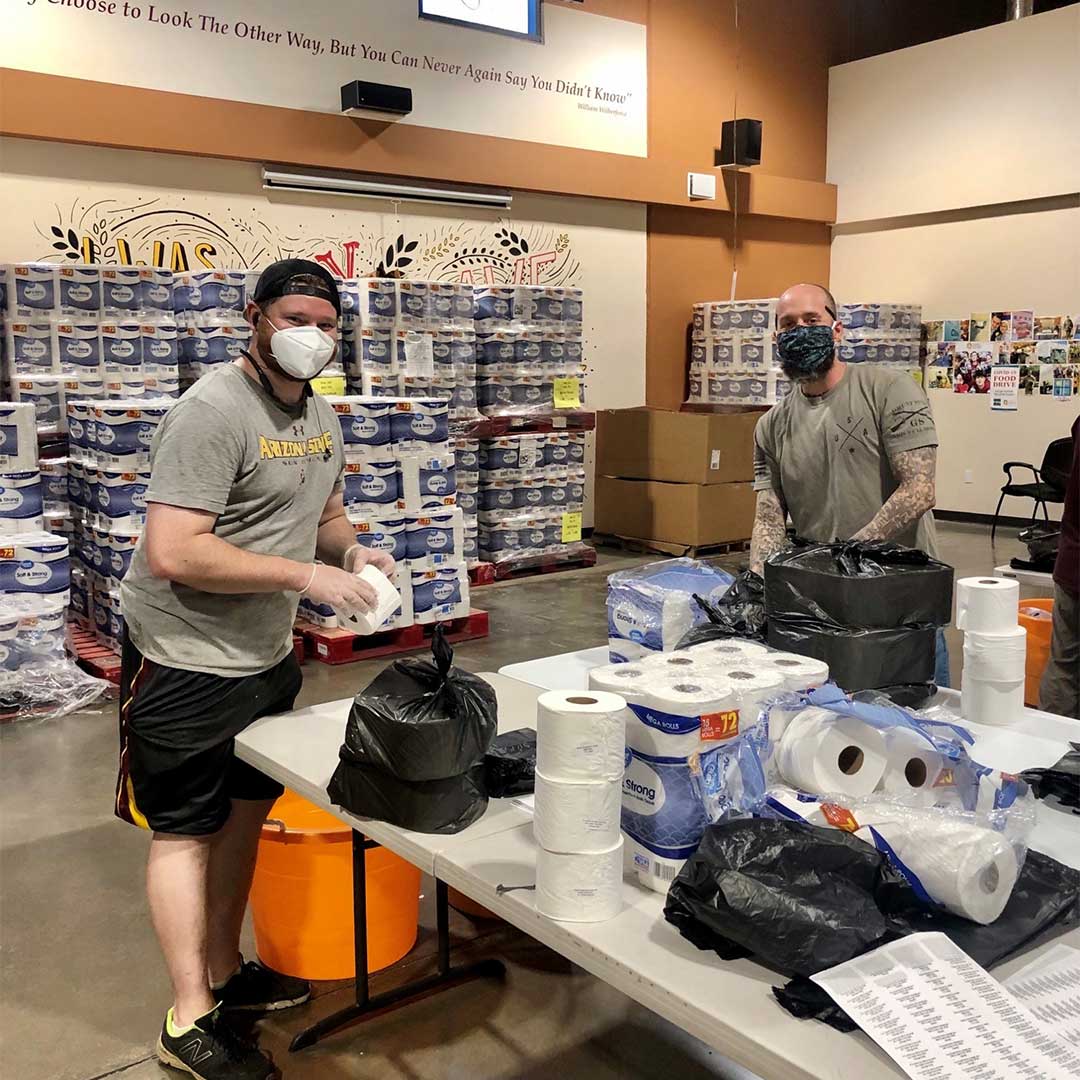 Tw o First Impression Ironworks employees packing boxes at Midwest Food Bank