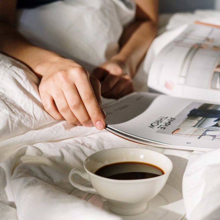 someone reading a magazine with coffee sitting to the side