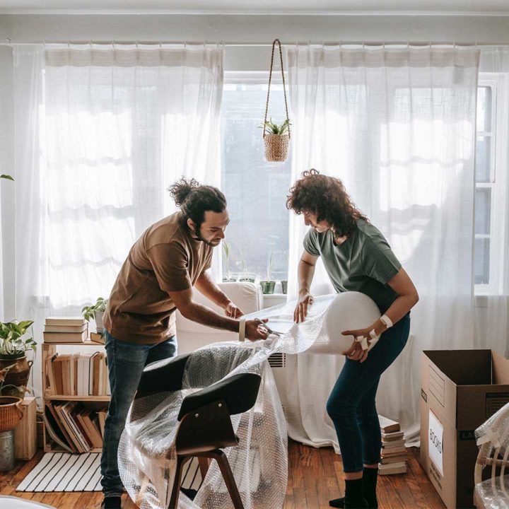 Two people wrapping a chair in bubble wrap