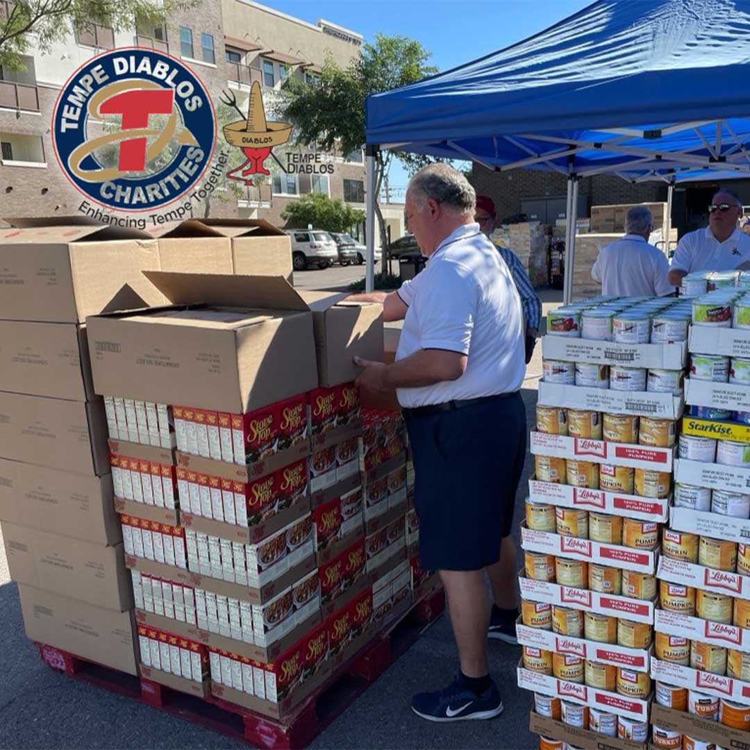 Cases of canned food stacked up with a man standing next to them