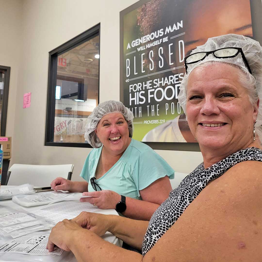 Two female First Impression Ironworks team members volunteering at Midwest Food Bank