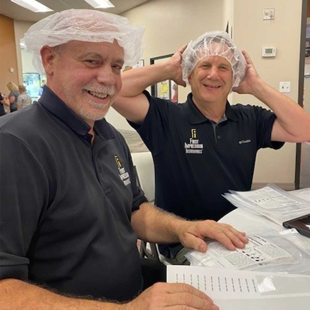 Two male First Impression Ironworks employees sorting through labels at Midwest Food Bank