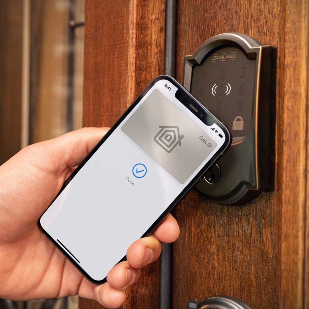 Hand holding a smart phone that is being used to open a lock on the front door of a home