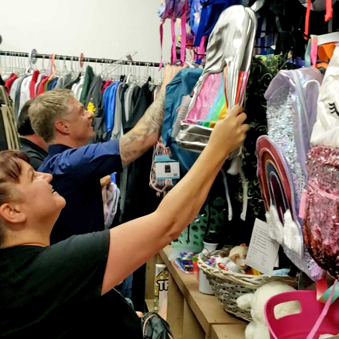 Two First Impression Ironworks Employees hanging backpacks on a wall at Backpacks 4 Kids AZ