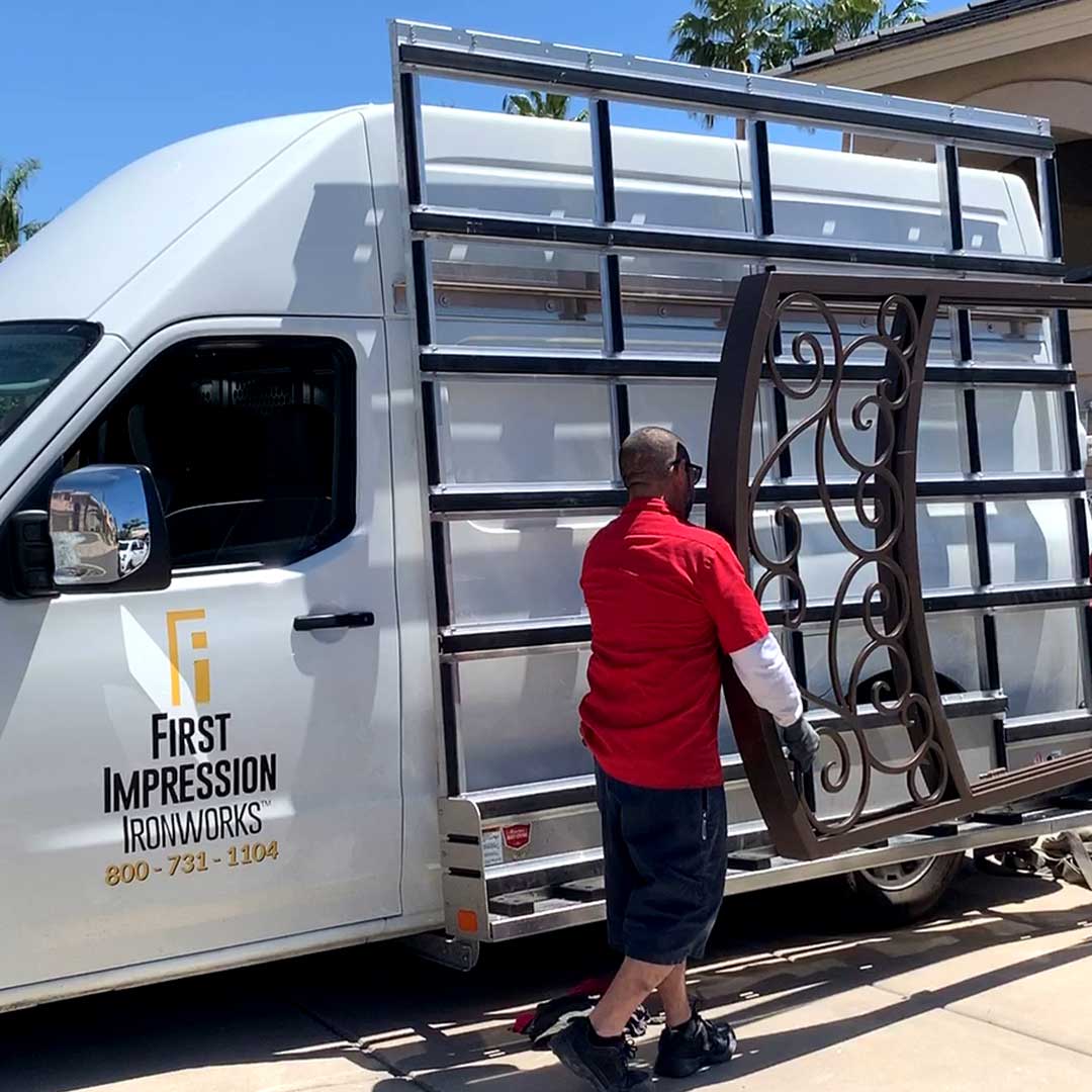 First Impression Ironworks installers carrying a large custom iron door to the front of a customer's home