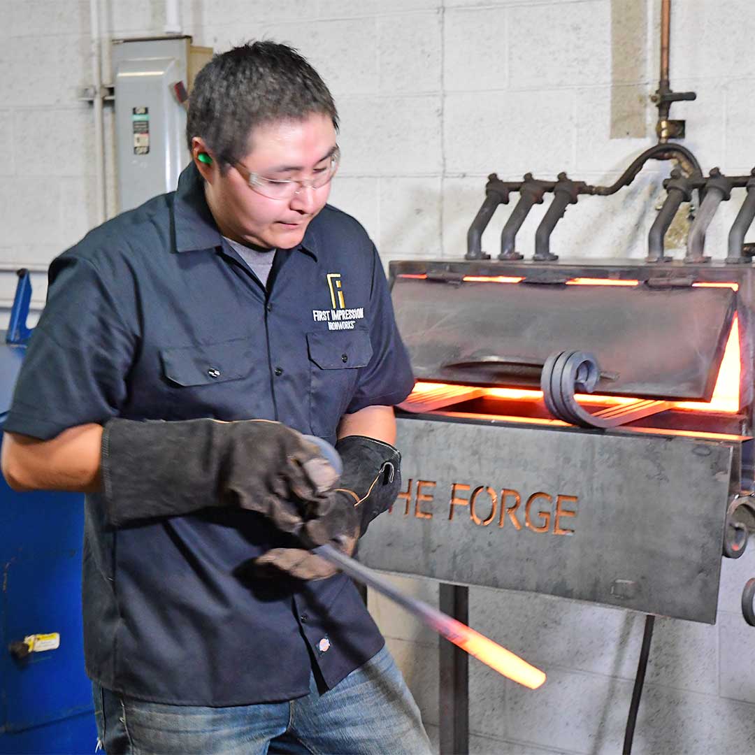 First Impression Ironworks artisan using the forge to hand craft iron door parts