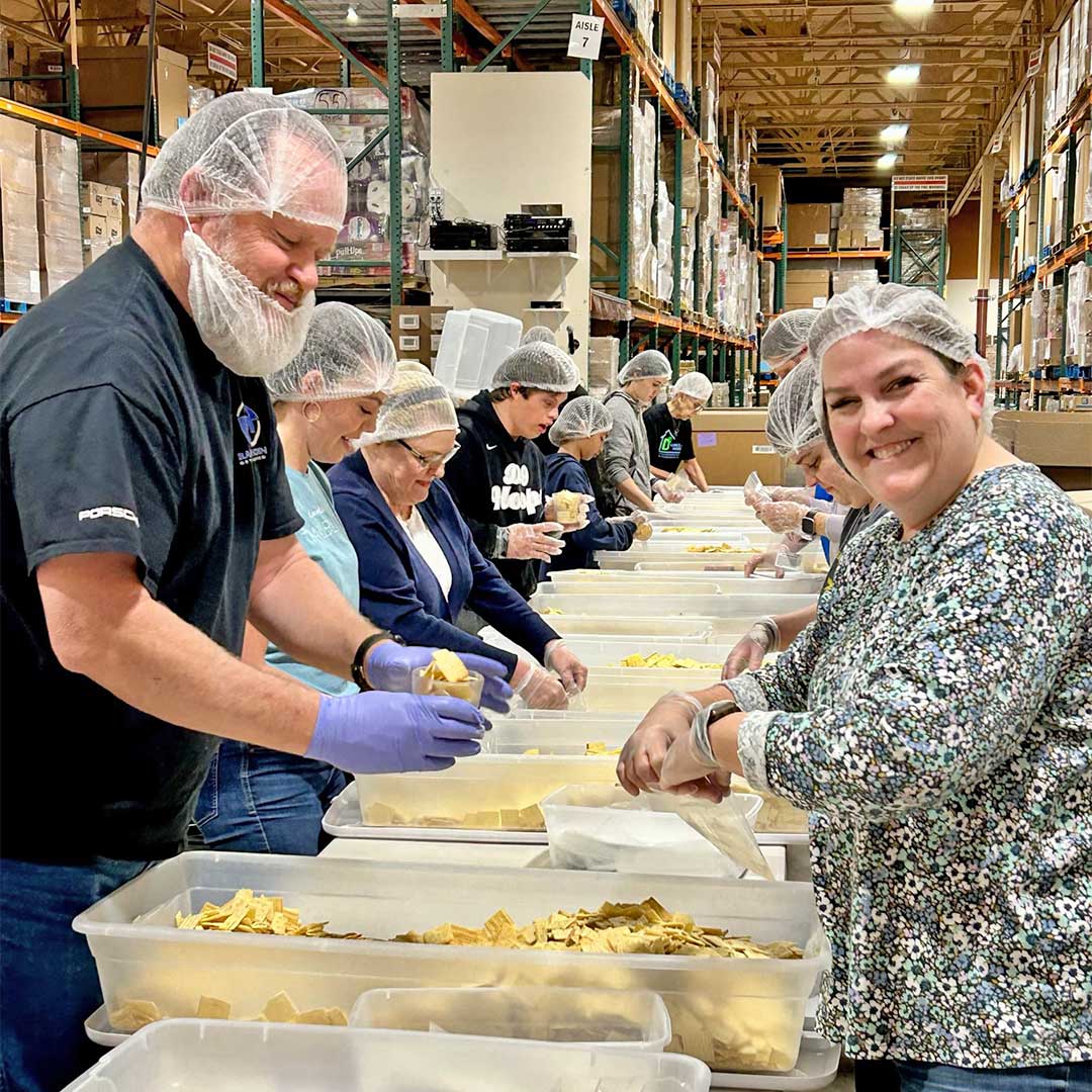 Many people packing food into individual serving bags at Midwest Food Bank