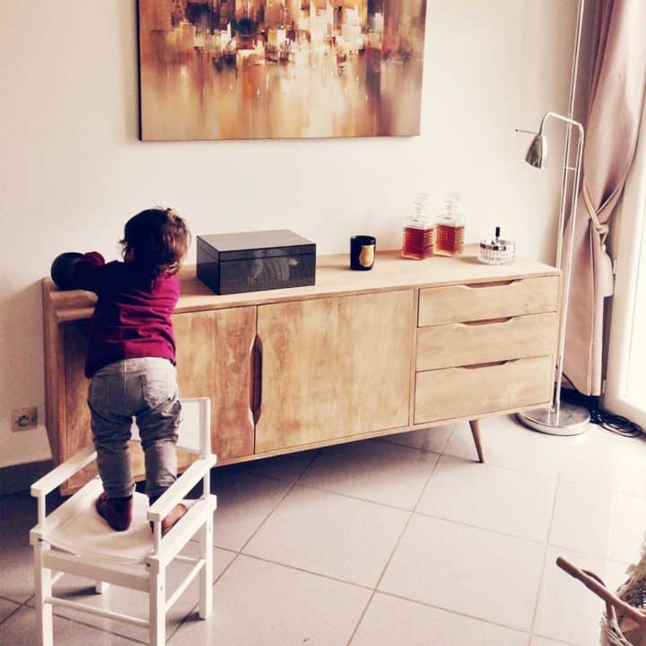 child standing on a chair to reach something on a console table