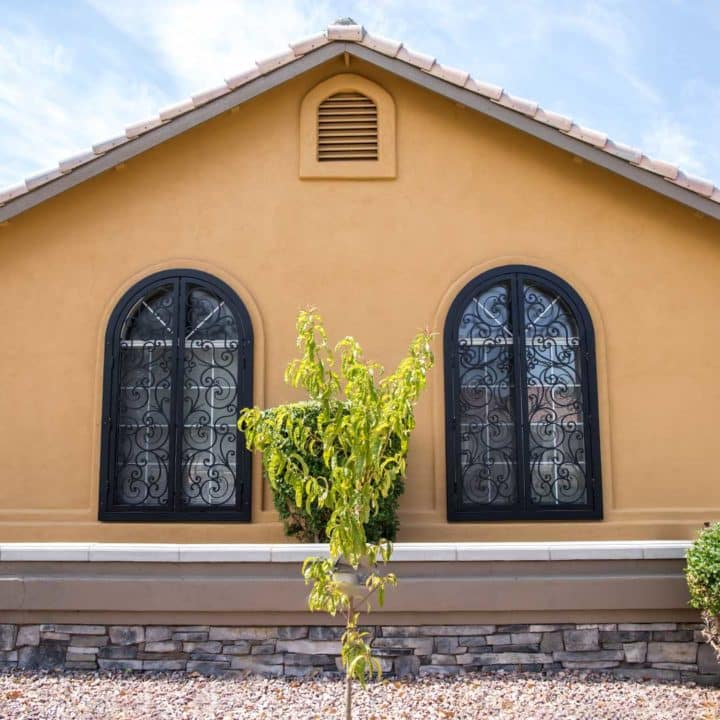 two arched window on the front of a home, with black decorative window guards