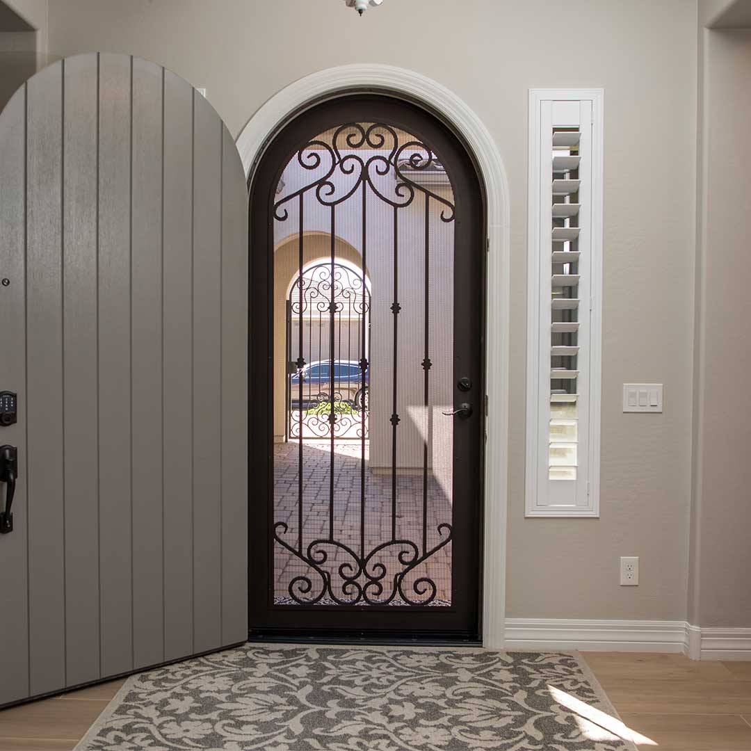 First Impression Ironworks Arched French Tip iron security door shown from the inside, with the interior wooden door open.
