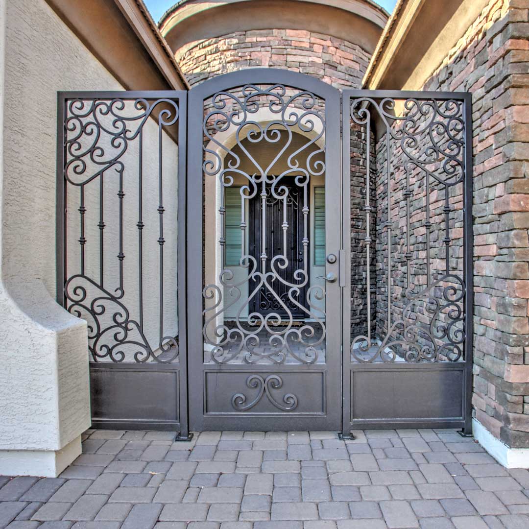 Arched iron courtyard gate gate by First Impression Ironworks with scrollwork