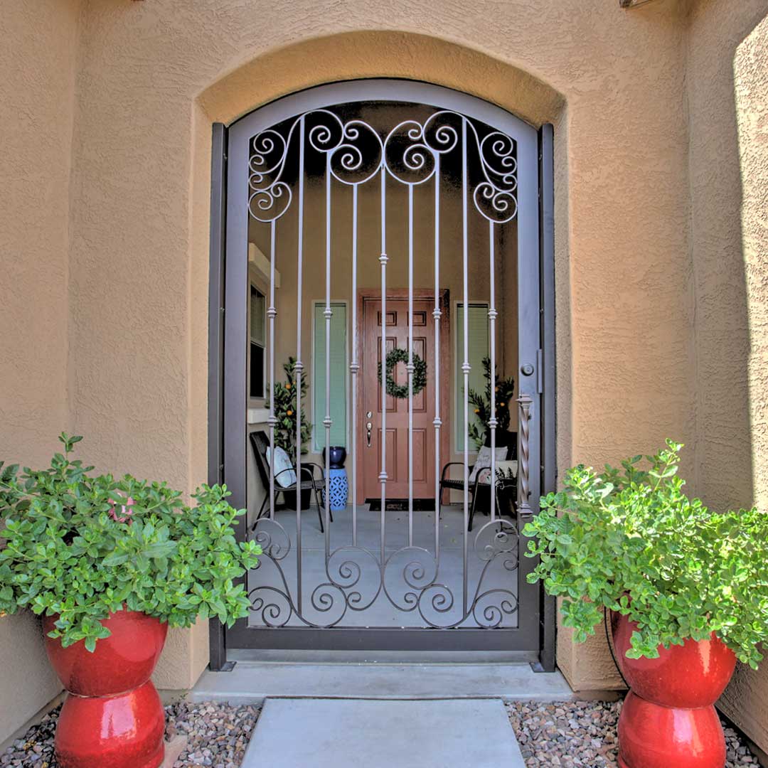 Arched First Impression Ironworks entry gate with intricate scrollwork designs