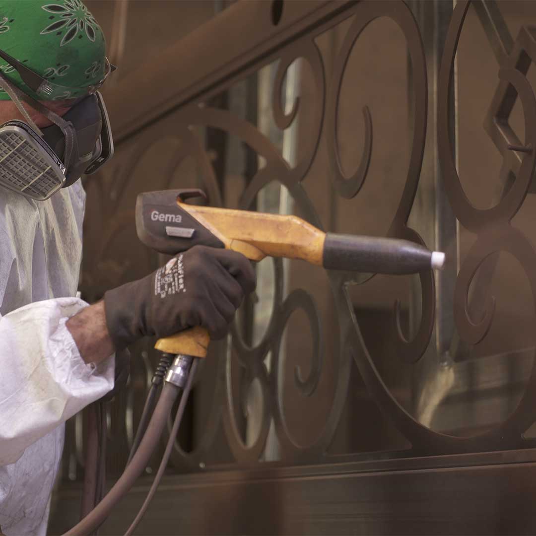 First Impression Ironworks employee powder coating an iron door