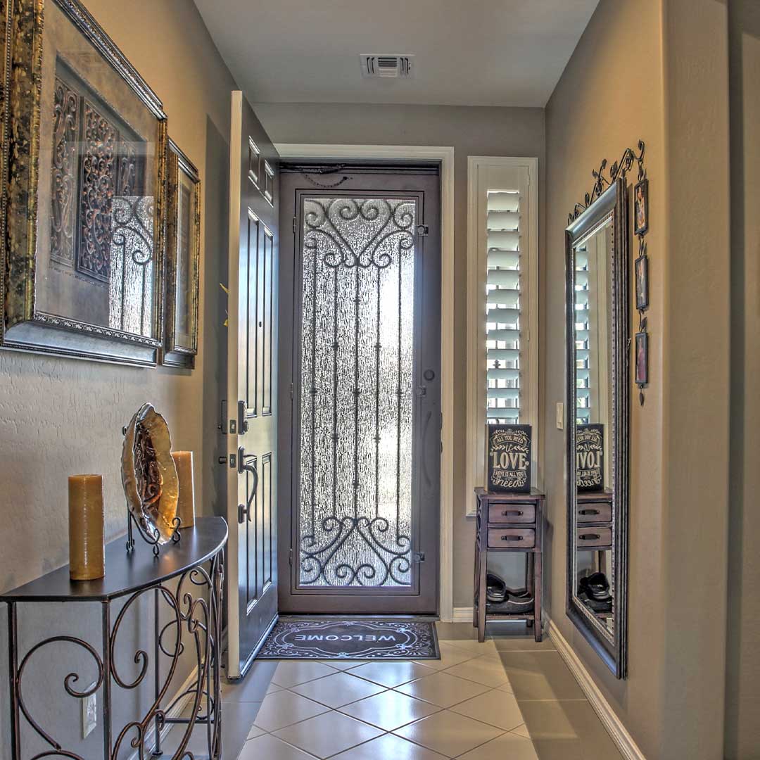 Front entry of a home, showing a wooden door open, with the FII Screen Door closed, allowing airflow through the home.