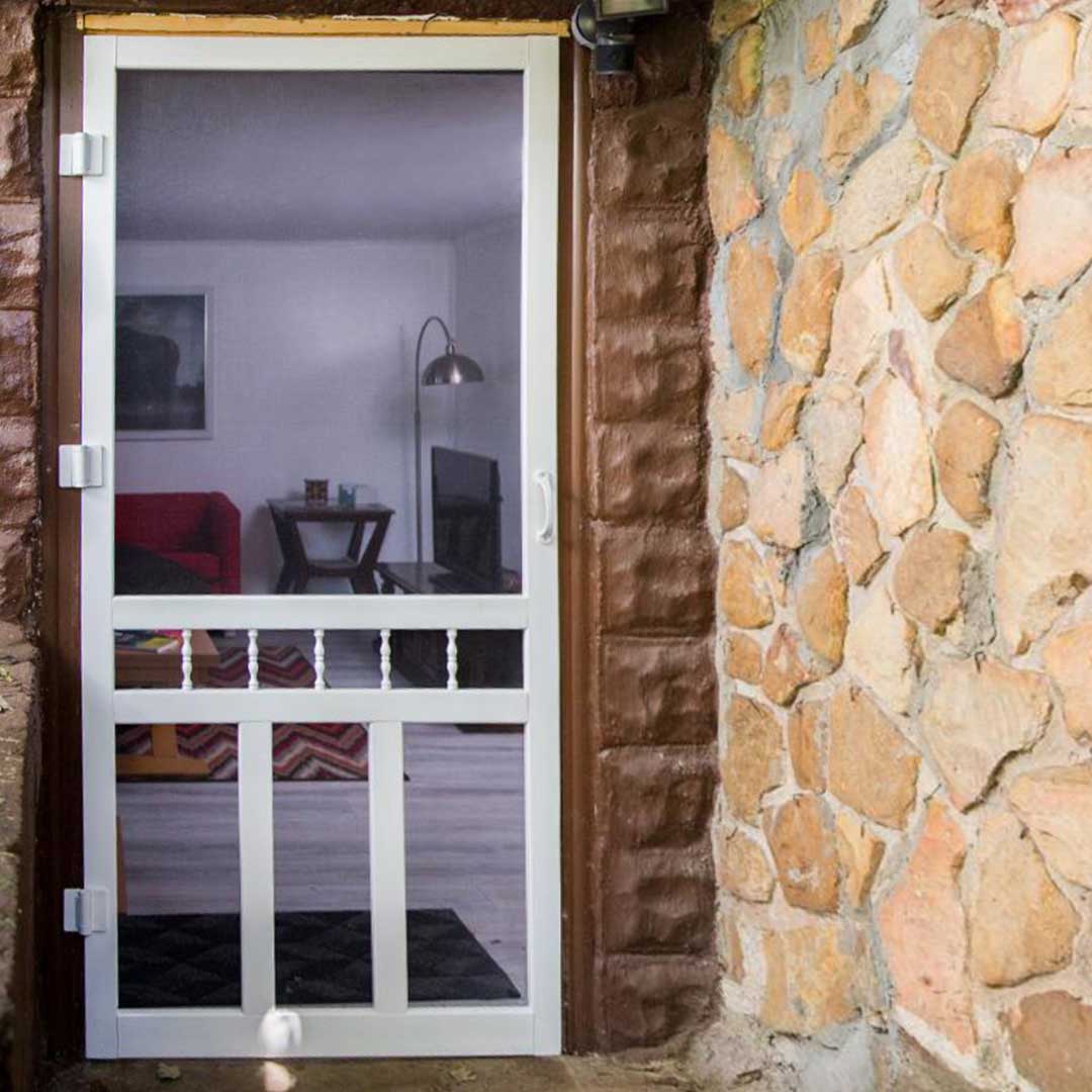 Close up of a white screen door, looking into a home.