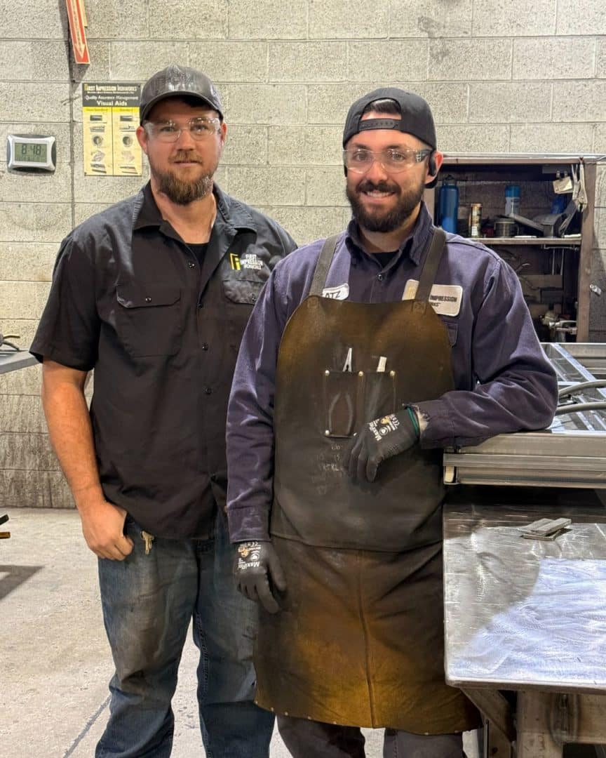 Two First Impression Ironworks team members smiling at the camera