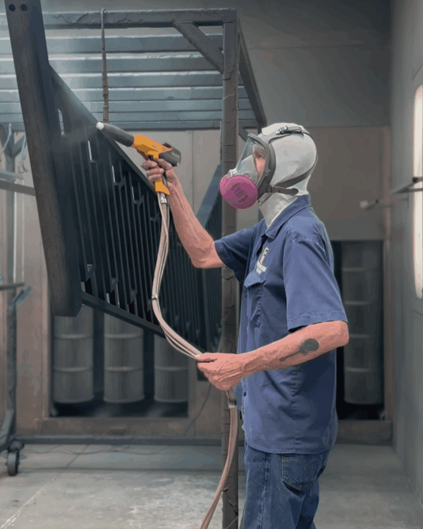 First Impression Ironworks employee spraying powder coat on a custom iron railing