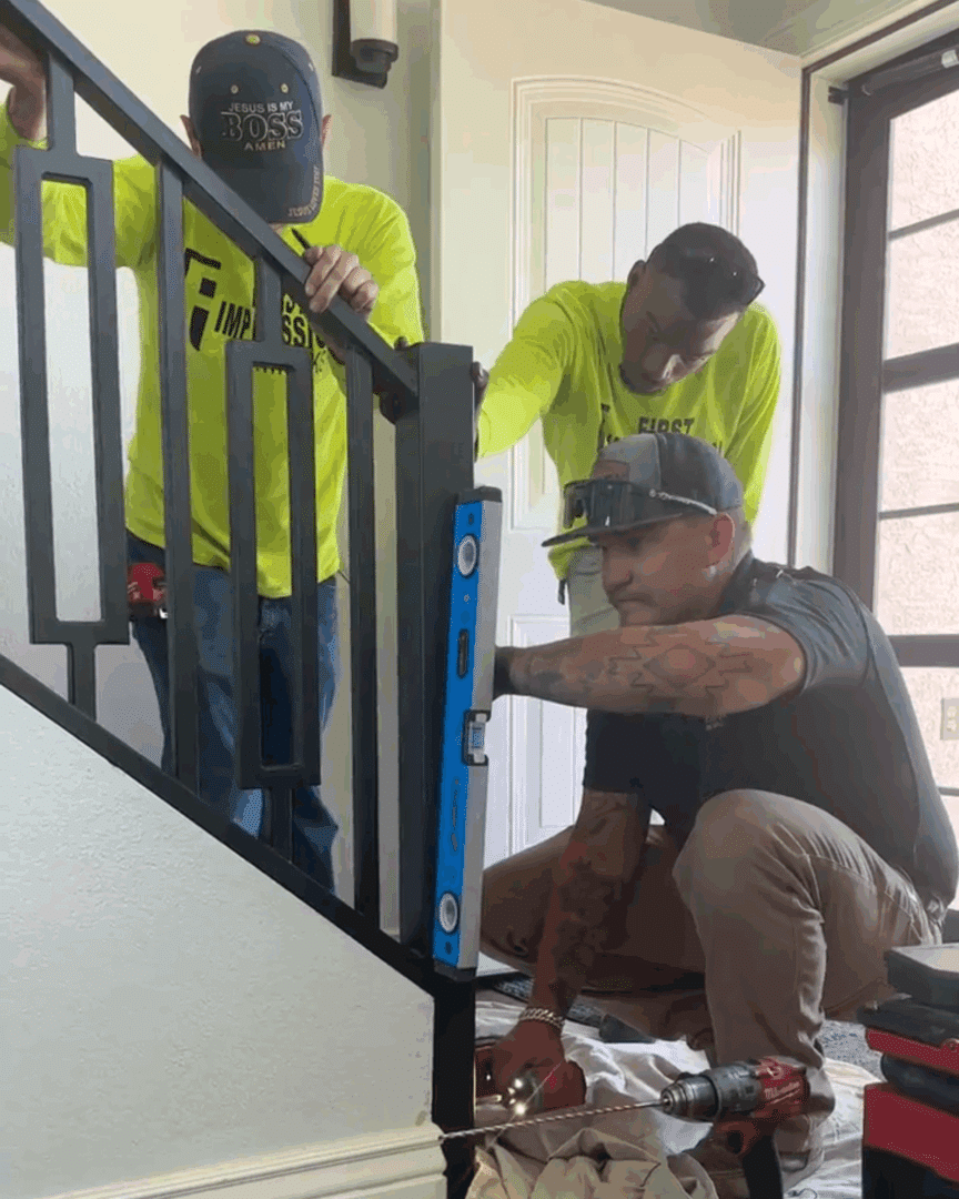Three First Impression Ironworks employees installing a new custom iron railing in a home