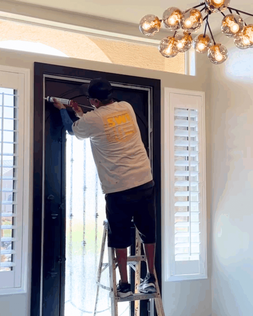 First Impression Ironworks installer adding caulk around the edges of the new iron door he is installing