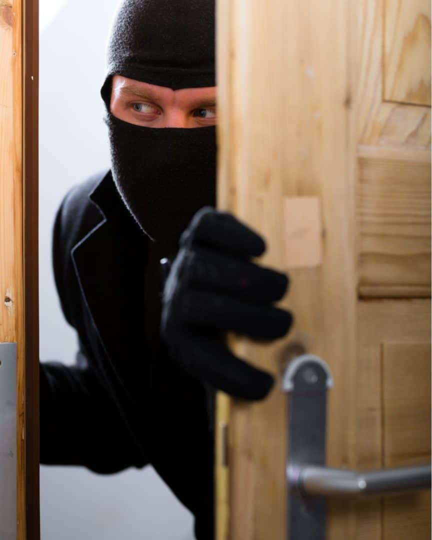 Burglar breaking into a home via a compromised wooden front door