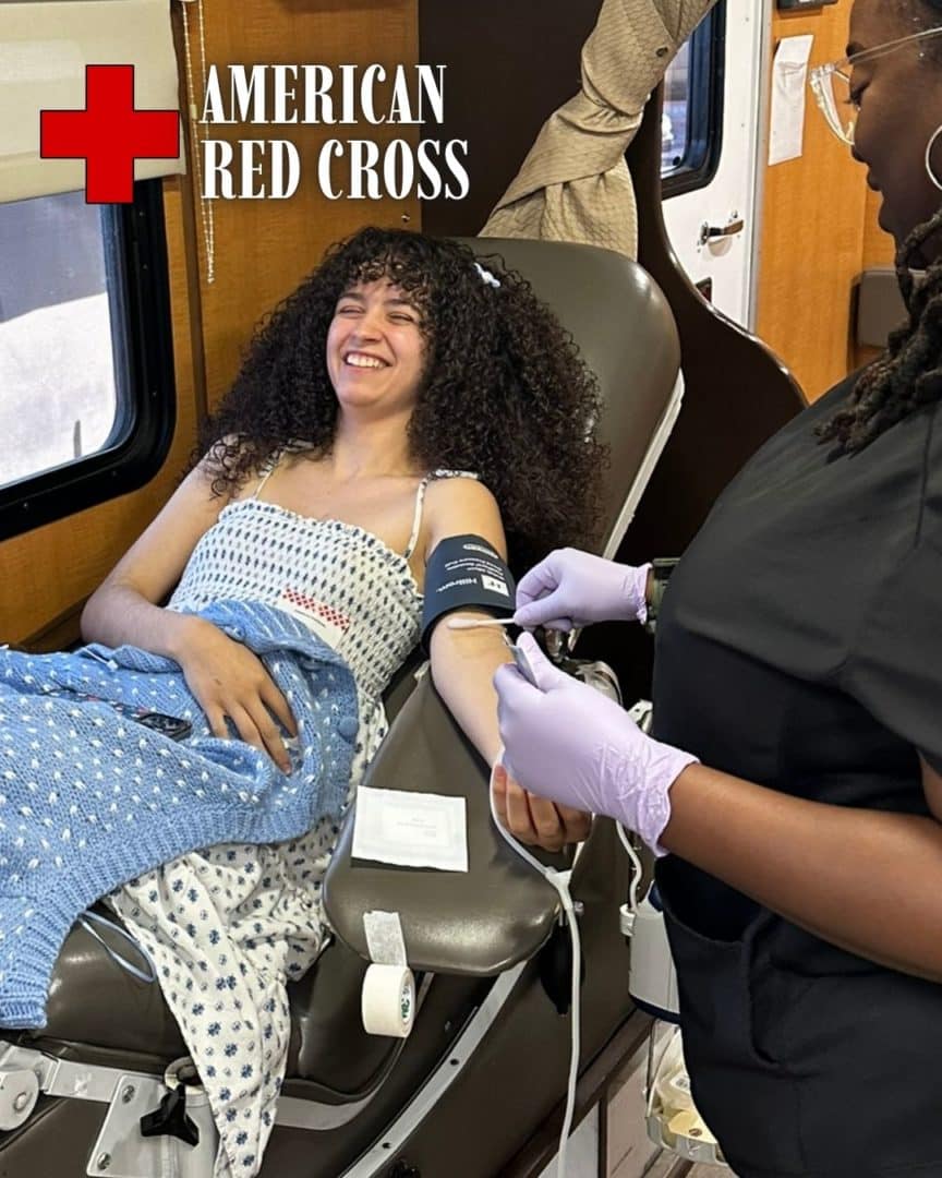 Member of the First Impression Ironworks team, laying on a bed while donating blood