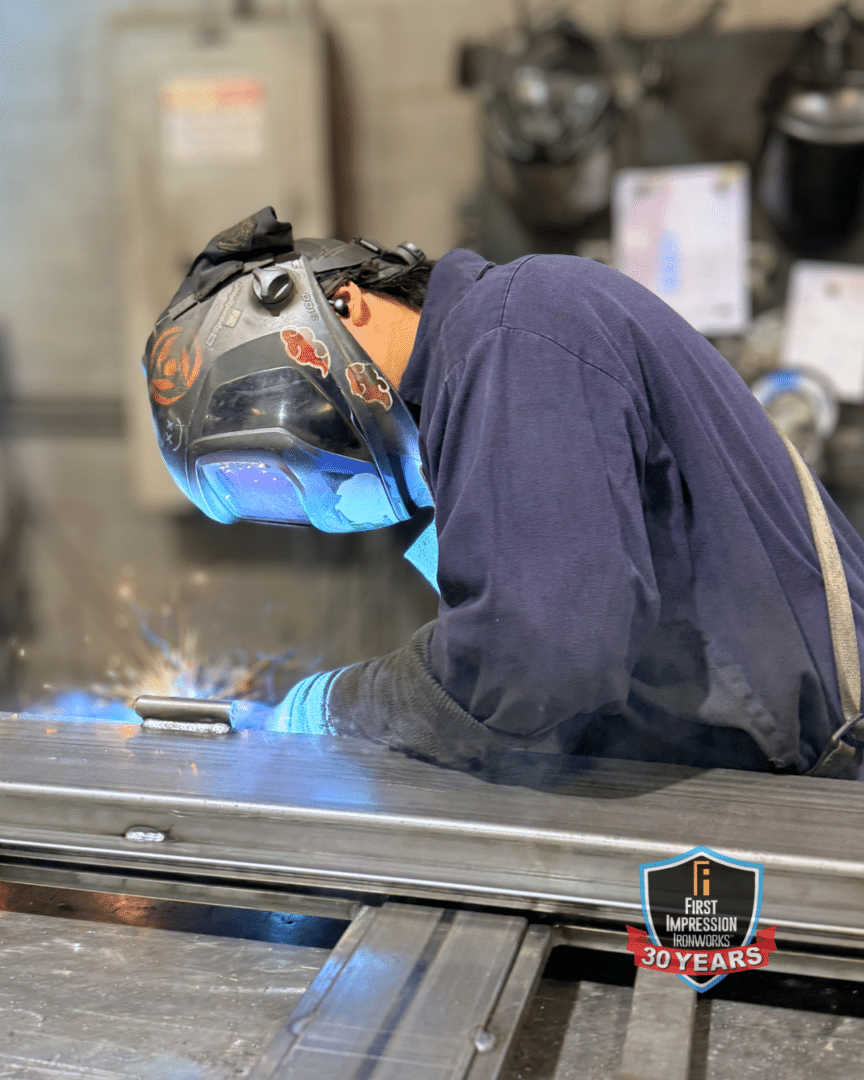 Welder working on a custom First Impression Ironworks door